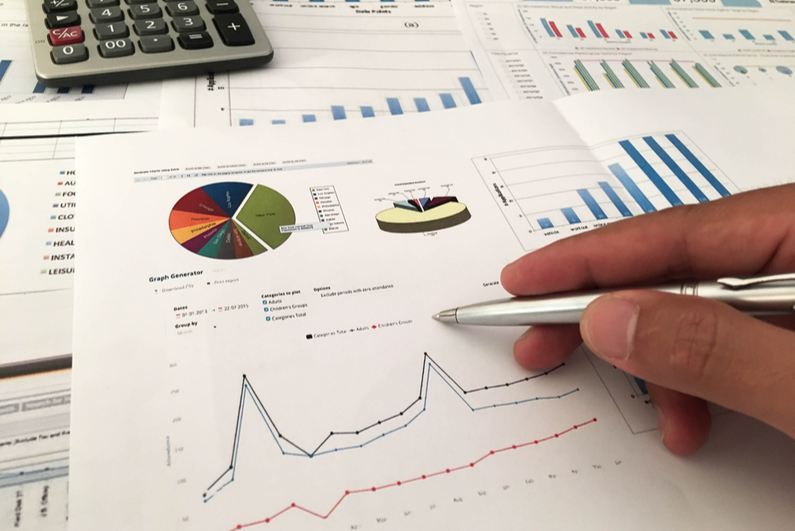 Hand with pen against chart of revenues