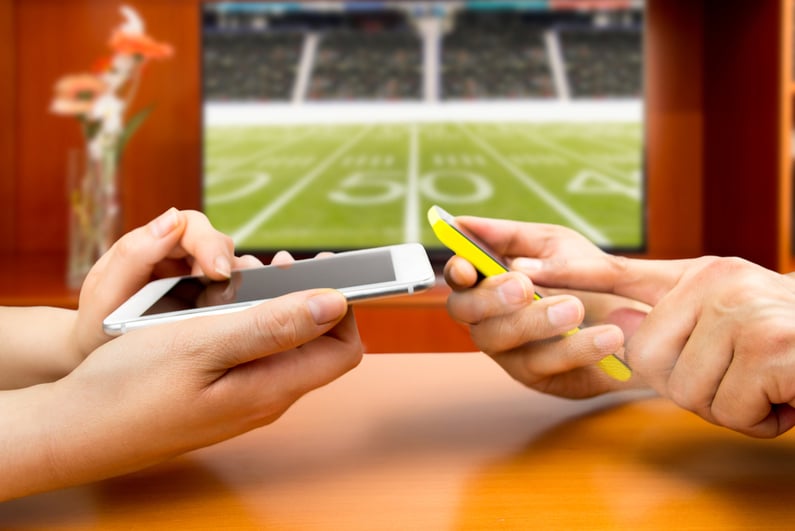 Friends using mobile phones and betting during a american football game