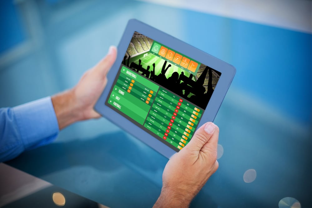 man's hands holding up tablet showing sports betting app