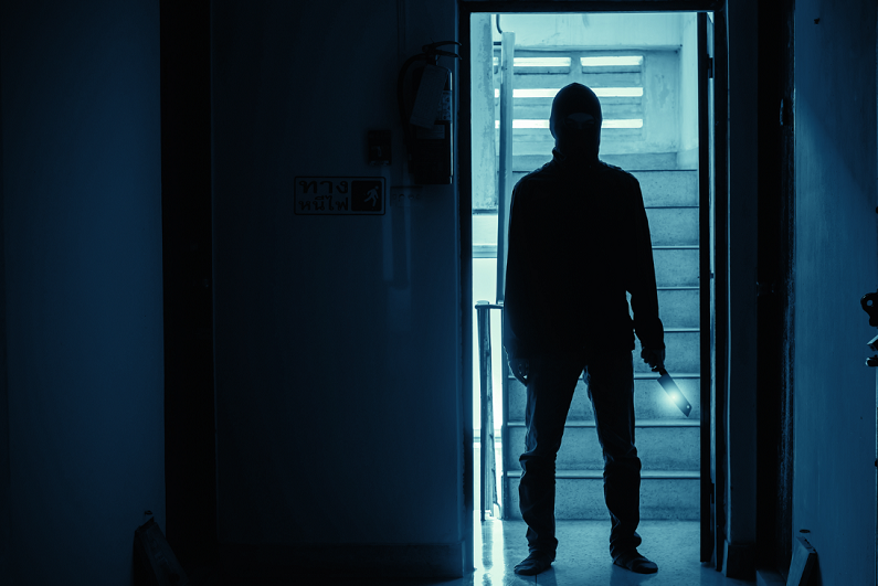 Silhouette of man holding knife inside a condo.