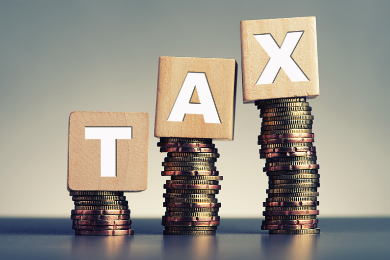 tax spelt on wooden blocks on stacked coins