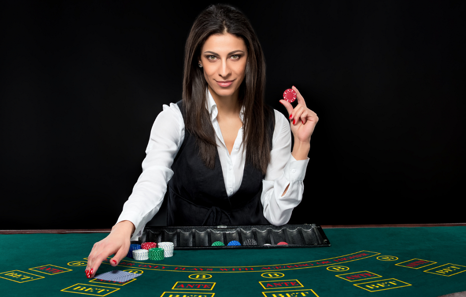 female dealer holding casino chip behind table