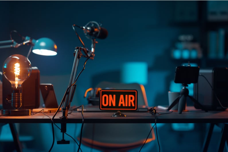 Podcast desk setup with "ON AIR" sign