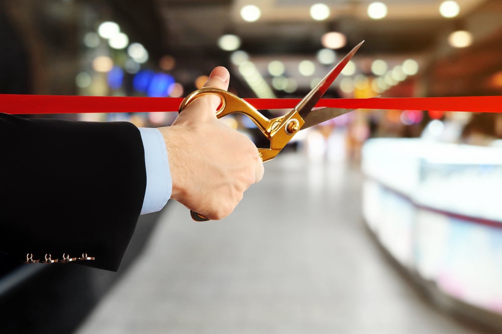 male's hand cuts ceremonial red ribbon at venue inauguration