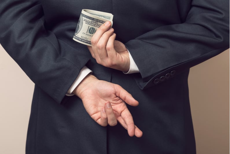 Businessman holding money and crossed fingers behind his back