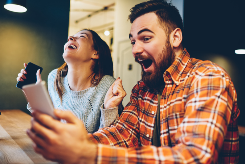 Man and woman cheering about something on their phones